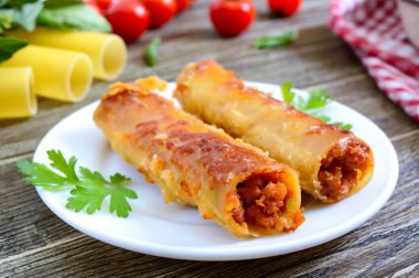 Beşamel sosu ile doldurulmuş içindeki cannelloni. Ahşap arka planda et, krem sos, peynir ile pişmiş cannelloni makarna.