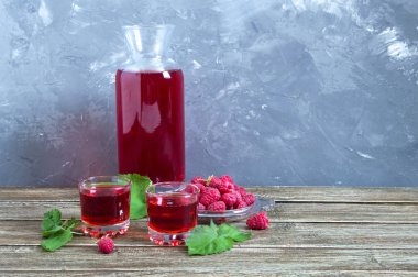 Cam ahududu likörü, rustik ahşap arka planda taze doğal olgun organik çilek ve yeşil yaprakları. Alkollü aromalı içecek.