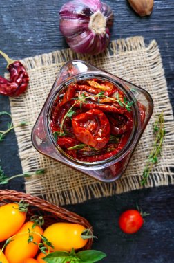 Otlar ile güneşte kurutulmuş domates, cam bir kavanozda zeytinyağı sarımsak. Üst görünüm, düz yatıyordu
