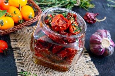 Otlar ile güneşte kurutulmuş domates, cam bir kavanozda zeytinyağı sarımsak.