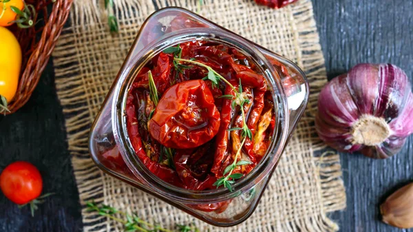 Otlar ile güneşte kurutulmuş domates, cam bir kavanozda zeytinyağı sarımsak. Üst görünüm, düz yatıyordu