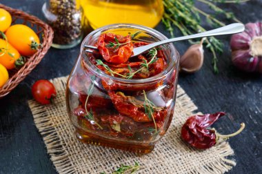 Otlar ile güneşte kurutulmuş domates, cam bir kavanozda zeytinyağı sarımsak.