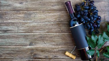 Kırmızı şarap, tirbuşon, mavi üzüm, ahşap bir masa üzerinde yaprakları ile Şişe. Kopya alanı ile şarap arka plan. Üst görünüm, düz yatıyordu