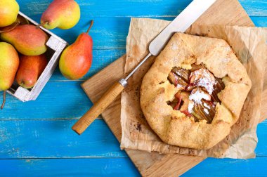 Mavi ahşap arka plan üzerinde tarçın ve kuru üzüm ile karamelize armut pasta. Lezzetli ve basit bir tatlı. Rustik tarz. Üstte görüntü.