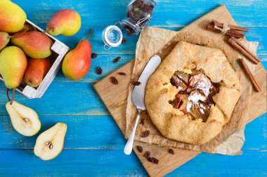 Mavi ahşap arka plan üzerinde tarçın ve kuru üzüm ile karamelize armut pasta. Lezzetli ve basit bir tatlı. Rustik tarz. Üstte görüntü.