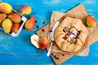 Mavi ahşap arka plan üzerinde tarçın ve kuru üzüm ile karamelize armut pasta. Lezzetli ve basit bir tatlı. Rustik tarz. Üstte görüntü.