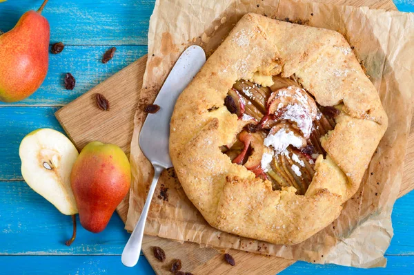 Mavi ahşap arka plan üzerinde tarçın ve kuru üzüm ile karamelize armut pasta. Lezzetli ve basit bir tatlı. Rustik tarz. Üstte görüntü.