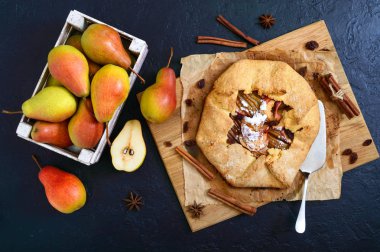 Siyah bir arka plan üzerinde tarçın ve kuru üzüm ile karamelize armut pasta. Lezzetli ve basit bir tatlı. Üstte görüntü.