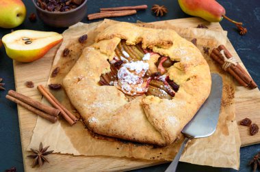 Siyah bir arka plan üzerinde tarçın ve kuru üzüm ile karamelize armut pasta. Lezzetli ve sade tatlı.