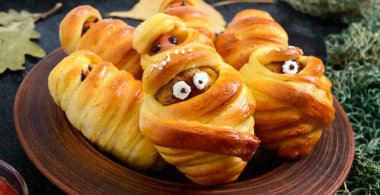 Komik sosis ve pirzola gözleri ile hamur mumyalar, masada ketçap. Cadılar Bayramı yemekleri.