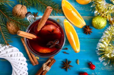 Noel, mavi ahşap bir kırsal masada baharatlı ve meyveli kırmızı şarap. Geleneksel tarçınlı sıcak içecek, kakule, portakal ve anason. Üst görünüm