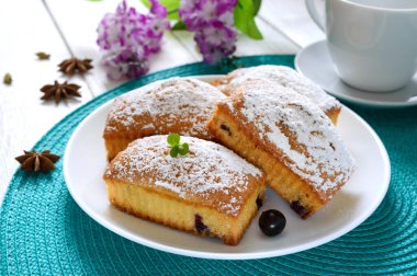 Böğürtlenli kekler ve beyaz ahşap arka planda bir tabakta krema şekeri. Dikdörtgen çörekler ve çay