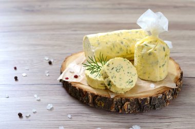 Butter with a herb for sandwiches and steak. Portion of Herb Butter sliced on a wooden board. Homemade italian food. Selective focus. clipart