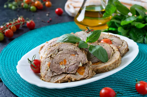 Delicious meat rolls stuffed with vegetables with cherry tomatoes and basil. Festive dish.