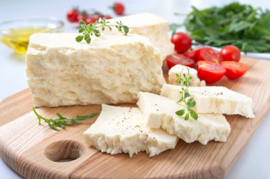Lezzetli koyun veya keçi peyniri. Beyaz arka planda ahşap bir tahtada Adighe peyniri parçaları. Çiftlik organik ürünleri.