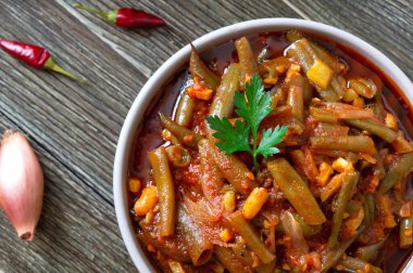 Ahşap arka planda bir kasede yeşil fasulye kabuğu domates lobisi. Ödünç al. Düz yerde, üst tarafta. Yakın plan.