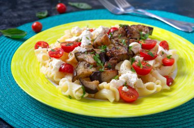 Izgara patlıcanlı makarna, kiraz domatesleri, keçi peyniri ve otlar. Lezzetli sıcak salata. Uygun beslenme.