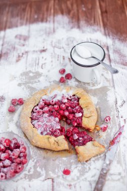 Ahşap masa üzerinde pudra şekeri ile taze ahududu ile yapılan ev yapımı meyve pasta (galette). Açık turta, ahududu turtası. Yaz dut tatlısı.