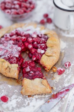Ahşap masa üzerinde pudra şekeri ile taze ahududu ile yapılan ev yapımı meyve pasta (galette). Açık turta, ahududu turtası. Yaz dut tatlısı. 