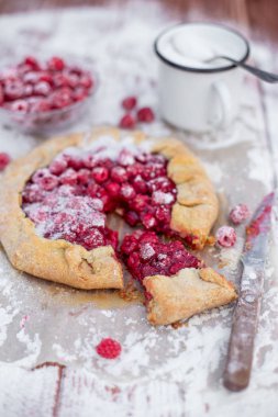 Ahşap masa üzerinde pudra şekeri ile taze ahududu ile yapılan ev yapımı meyve pasta (galette). Açık turta, ahududu turtası. Yaz dut tatlısı. 