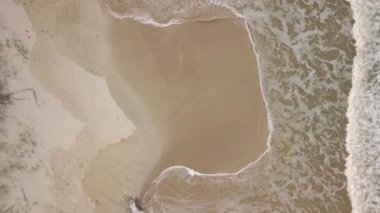 Dron hava görüntüsü dalgalar beyaz kumsalda kırılıyor. Üst görünüm.