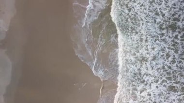 Dron hava görüntüsü dalgalar beyaz kumsalda kırılıyor. Üst görünüm.