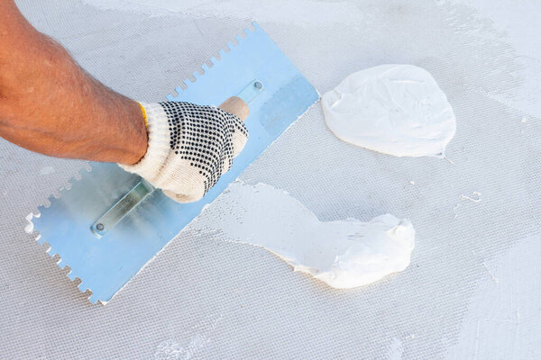 Builder using plastering tool for finishing wall and floor