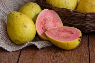 Ahşap arka planda sepetle kesilmiş guava meyvesi fotoğrafı.