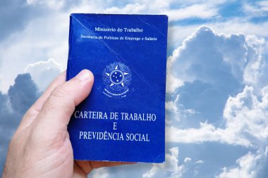 Brezilya iş kartını tutan adamın eli mavi gökyüzünde ve bulutların arkasında izole. Portekiz Federatif Brezilya Cumhuriyeti, Çalışma Bakanlığı 'nda yazılmıştır. Çalışma ve Sosyal Güvenlik kartı. Brezilya iş konsepti