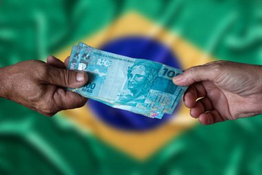 Brezilya para faturaları. 100 reais. Brezilya bayraklı yüz reais banknot tutan erkek ve kadının eli bulanık arkaplan