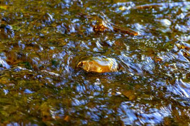 Arka plan. Kristal berraklığında su kayaları akar.