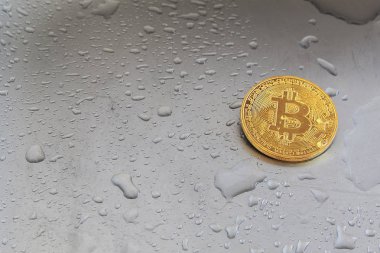 Altın bitcoin metal yüzeyi ile su damlaları.