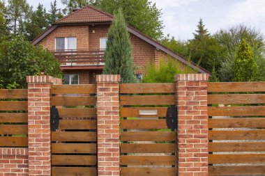 Güzel kırsal tuğla ev yeşil ağaçlar arasında ahşap bir çit arkasında