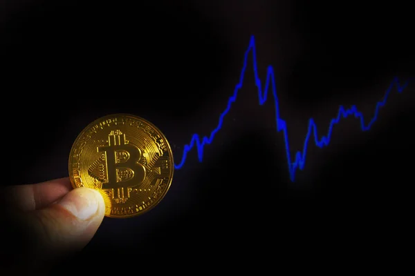 Bir grafik ile karanlık bir arka plan üzerinde bir para bitcoin parmak tutun