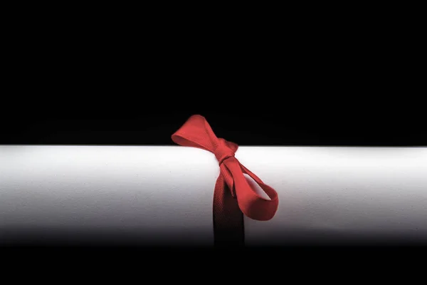 Beyaz kağıt bir rulo siyah bir zemin üzerine kırmızı kurdele ile bağlanmış