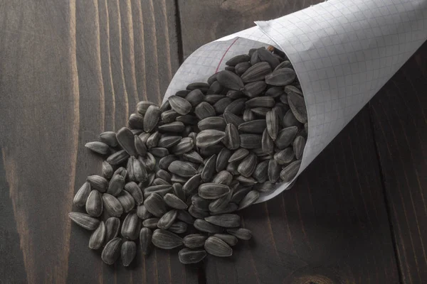 Black seeds are scattered on an old dark wooden table