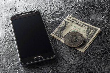 Karanlık bir arka plan üzerinde telefon, dolar ve para bitcoin