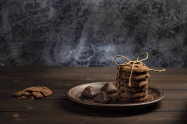 Çikolata bisküvi ip, karanlık bir arka plan ile ahşap bir masa üzerinde kahverengi plaka ile sargılı