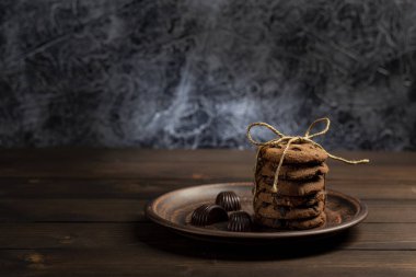 Çikolata bisküvi ip, karanlık bir arka plan ile ahşap bir masa üzerinde kahverengi plaka ile sargılı
