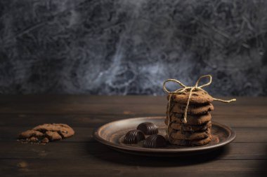 Çikolata bisküvi ip, karanlık bir arka plan ile ahşap bir masa üzerinde kahverengi plaka ile sargılı