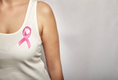 Göğsünde pembe kurdele olan beyaz tişörtlü bir kız..