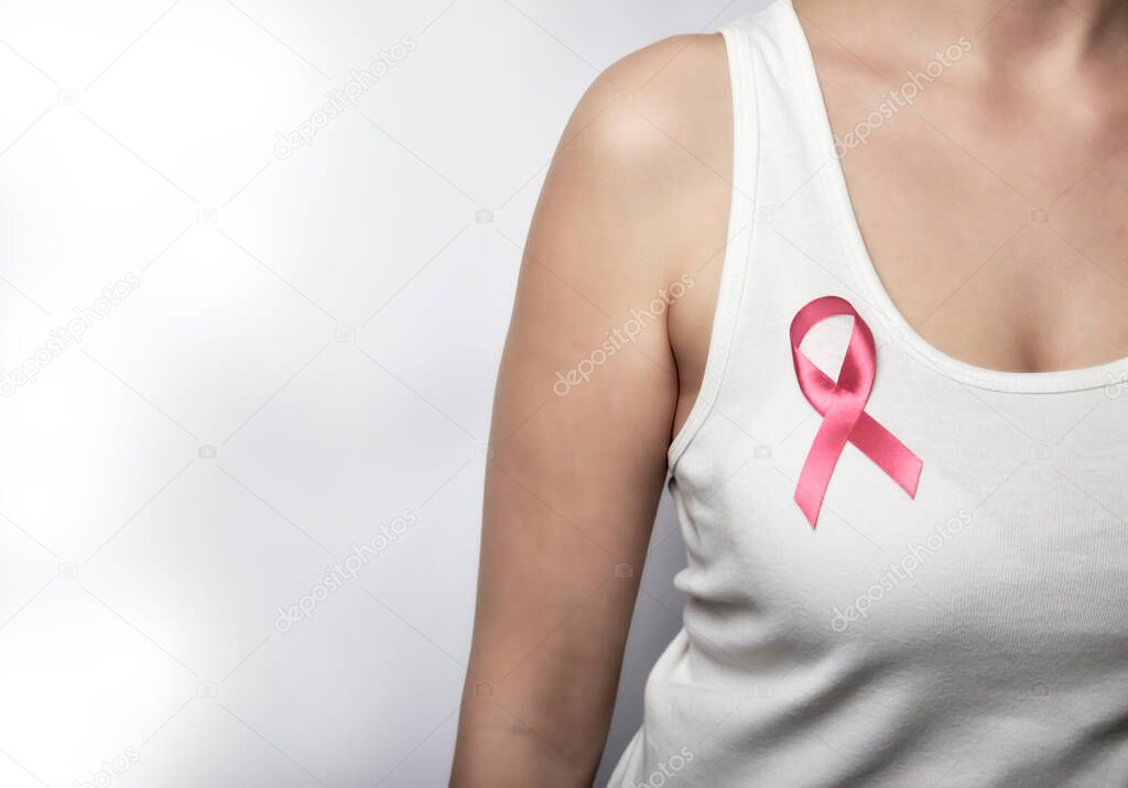 Girl in a white T-shirt with a pink ribbon on her chest.