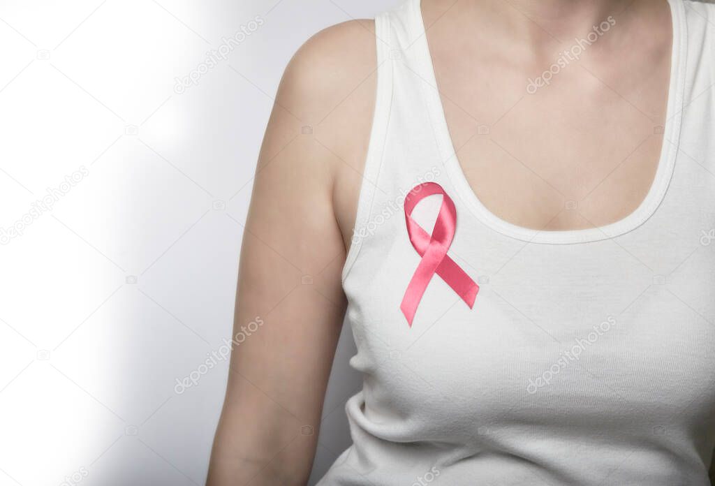 Girl in a white T-shirt with a pink ribbon on her chest.
