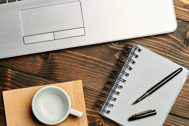 Diz üstü bilgisayarı, üzerinde kahve defteri olan tahta kalemle çatı kaplama. Çalışma tablosu görünümü en üstten.