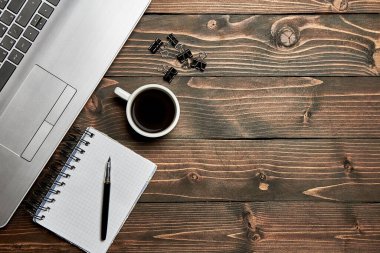 Diz üstü bilgisayarı, üzerinde kahve defteri olan tahta kalemle çatı kaplama. Çalışma tablosu görünümü en üstten.