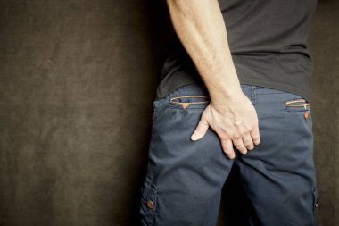 A man holds himself for the ass. The priest hurts. Hemorrhoids