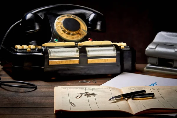 Eski siyah telefon kağıtları ve koyu arkaplan üzerine mürekkep kalemle sığ alan derinliği ve bulanıklığı olan eski masaüstü.