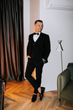 Man in formal attire poses confidently in modern living room during evening event