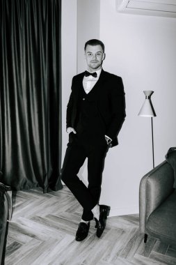 Stylish man in formal attire poses elegantly in a modern indoor setting during evening event