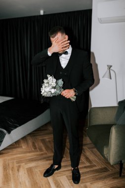 Groom expresses emotions while holding a bouquet before a wedding celebration